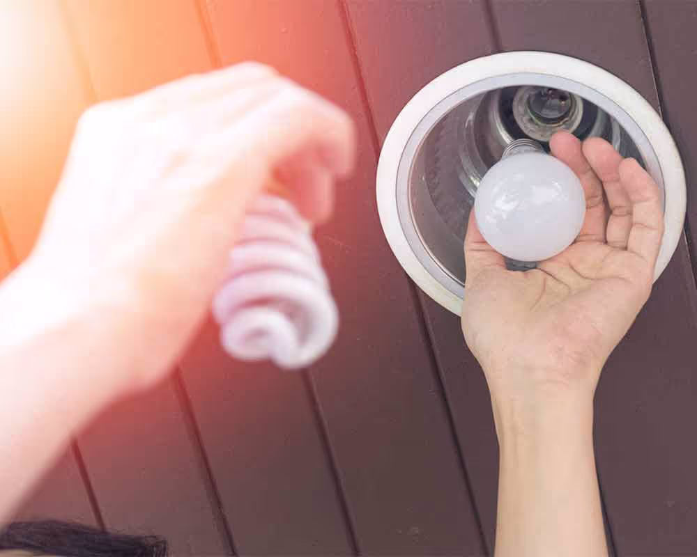 Handyman on ladder changing a light bulb in ceiling fixture