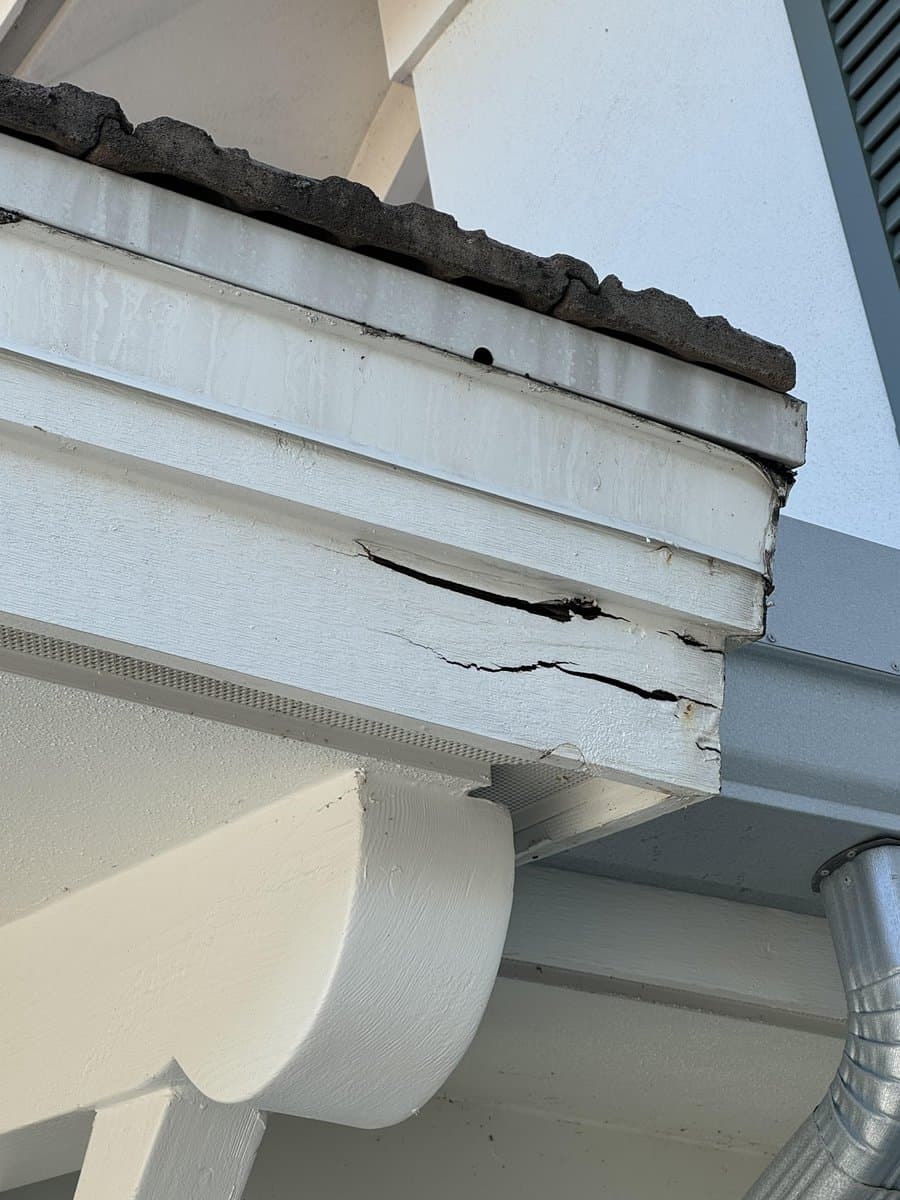 Cracked and rotted fascia board at roofline showing wood damage