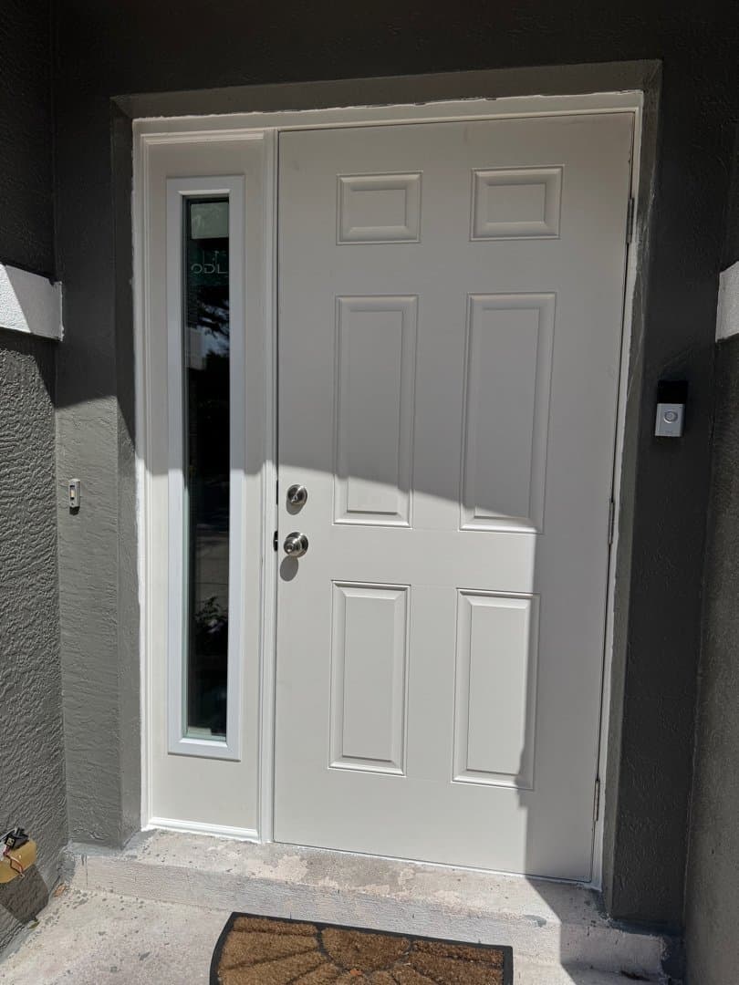 New white 6-panel front door with glass sidelight and modern hardware installed