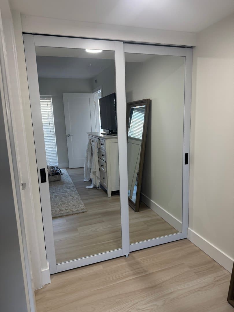 Mirrored sliding closet doors and upper storage cabinets installed in laundry room
