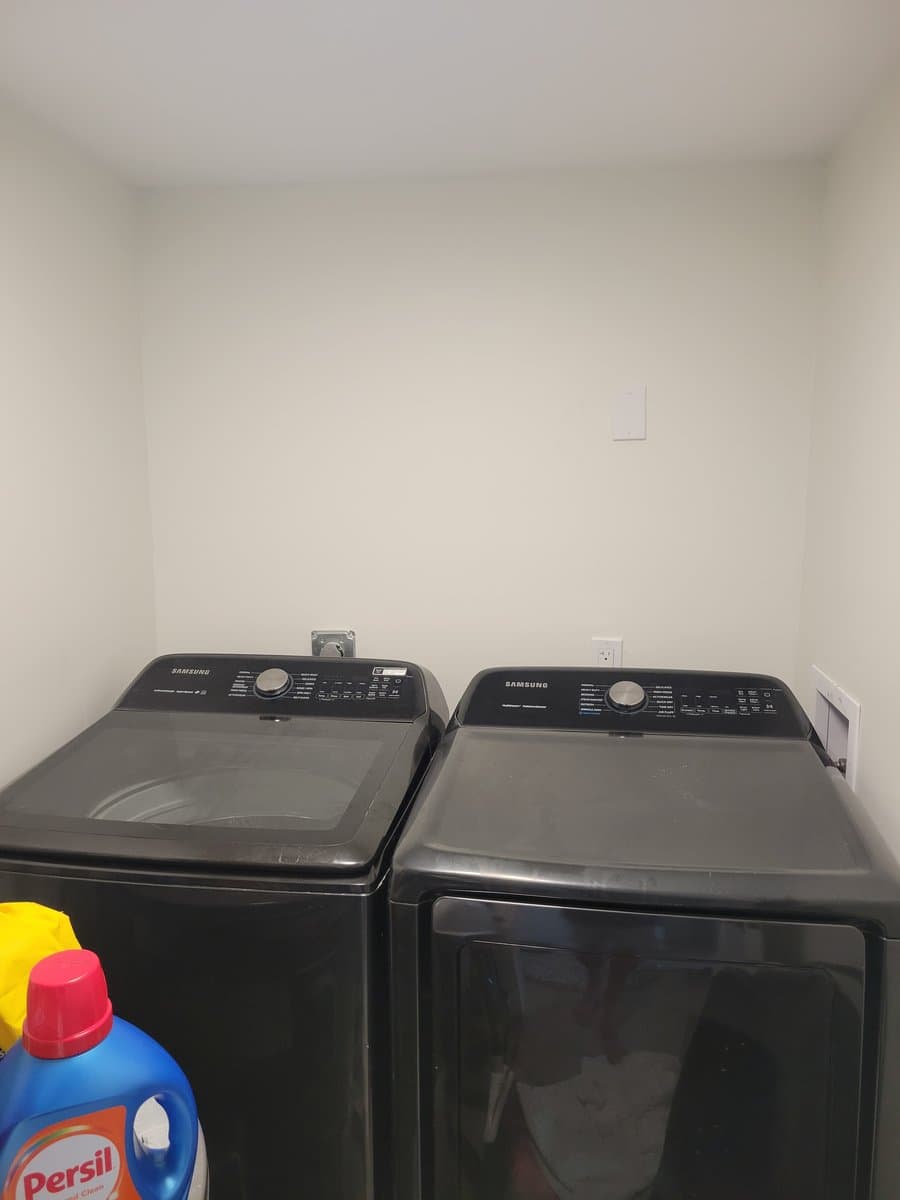 Bare laundry room with washer and dryer against plain wall