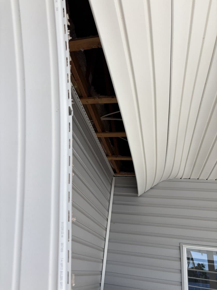 Storm-damaged lanai soffit with exposed framing and missing panels